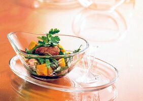 Glass bowl of salad with chopped pumpkin and meat kept on glass plate