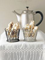 Peanut bars in black and silver basket with kettle on white tablecloth