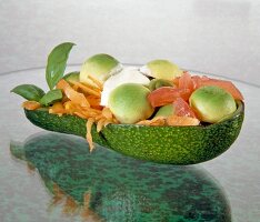 Halved avocado topped with tomatoes, carrots and spring onions