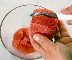 Close-up of grapefruit fruit fillets being cut with a knife