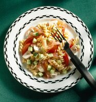 Pasta salad with tomato, cucumber, mushrooms and smoked ham on plate