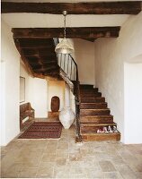 View of old oak staircase with stone floor and wooden bench