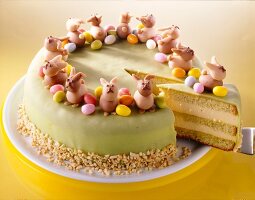 Easter cake with pineapple, marzipan bunnies and eggs on plate with one piece on spatula