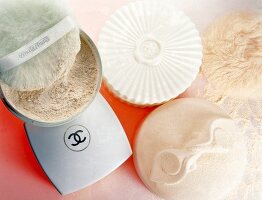 Various bright coloured compact powders and powder puffs, overhead view