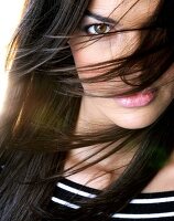 Portrait of gray eyed pretty woman with windswept long dark hair, close-up