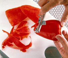 Close-up of hands peeling red pepper