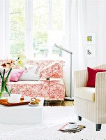 Wohnzimmer mit Sofa, Korbsessel in Rosa, Rot, Blütenmuster, weiss