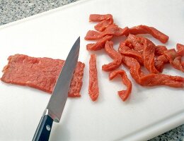 Beef cut in slices with a sharp knife on a cutting board