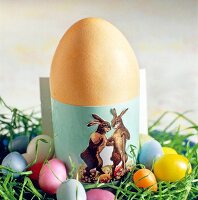 Ei im grünen Eierbecher mit Osterbil d dekoriert.