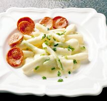 Salsify and spring onions with fried meat sausage on plate