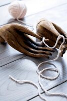 Carved wooden hands with woollen thread on table