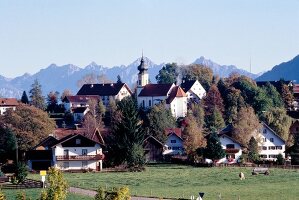Blick auf das Dorf Wildsteig in Bayern mit Zwiebelturmkirche, Berge
