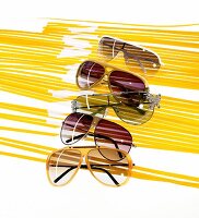 Close-up of five different types of aviator sunglasses on yellow strips