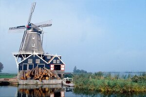 Landschaft: Windmühle am See, blauer Himmel.