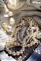 Close-up of various pearl jewellery on knitted scarf