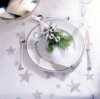 Napkin wrapped with Christmas decoration on plate with knife and fork on table