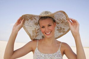 Jennifer Fröhliche junge Frau am Strand mit einem großen Strohhut