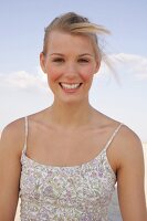 Portrait of beautiful woman in floral pattern dress standing on beach, smiling