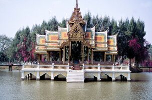Thailändischer Tempel mit verzierten Dächern auf Pfählen im Fluss