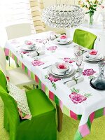 Chairs, lamp and table laid with floral tablecloth and plates