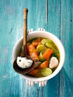 Fish sweet potato curry with tarragon cream in bowl on wooden surface