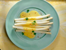 Asparagus with saffron- parsley sauce and herbs on plate