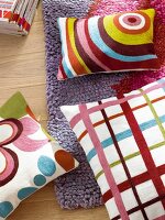 Colourful pillows in three different patterns lying on wool rug