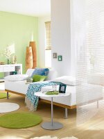 Wohnzimmer in Grüntönen mit weißem Sofa, hohe Bambusvasen in der Ecke
