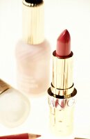 Red lipstick, nail polish and other products on white background