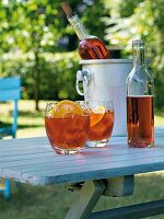 Glasses and bottle of campari cooler on wooden table