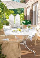 Helle Terrasse mit Korbmöbeln, Tisch mit Geschirr