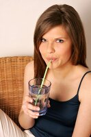 Portrait of woman with long hair drinking water with straw, smiling