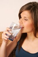 Portrait of woman with long hair drinking a glass of water