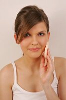 Portrait of pretty woman with brown hair cleaning her face with pad