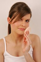 Portrait of gray eyed Magdalena woman with brown hair applying make-up with a sponge