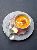 Pumpkin and potato soup with apple slice in bowl