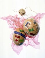 Package of mache eggs with stamps on pink fabric against white background