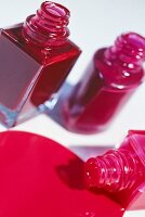Close-up of three red and pink nail polish bottles