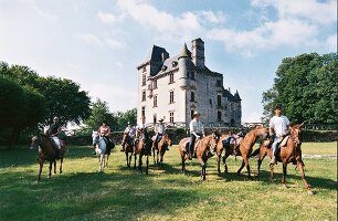 Menschengruppe reitet auf Wiese vor Schloss, Sommer, Frankreich