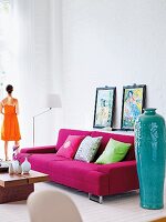 A living room with a high ceiling, a pink sofa and oriental decorative objects