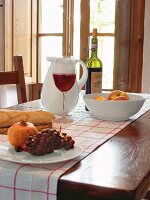 Carafe, fruits and glass of red wine on table in front of window