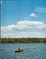 Two men rowing a flatboat in river