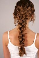 Rear view of woman with braided brown hair wearing white spaghetti top