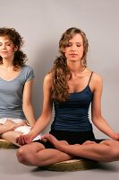 Two women sitting and performing yoga