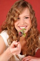 Frau führt Gabel mit Salat zum Mund
