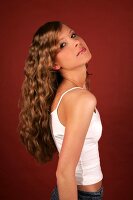 Portrait of beautiful woman with long curly hair wearing white top standing and smiling