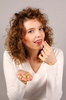 Portrait of beautiful woman with curly hair wearing white sweater holding pill, smiling