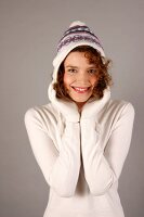 Portrait of beautiful woman with curly hair wearing white sweater and cap, smiling widely