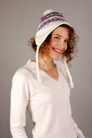 Portrait of beautiful woman with curly hair wearing white sweater and cap, smiling widely