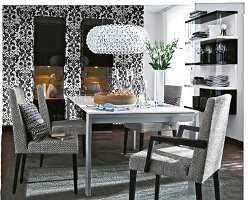 Dining room in black and white with floral motifs on wall and glass chandelier